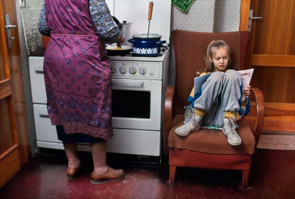 Steve McCurry "Ein Mädchen liest, während ihre Großmutter kocht", Flechtingen, Deutschland 1990